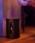 Sub Mini Compact Wireless Subwoofer For Beam And Ray with deep bass beside seated person, black finish