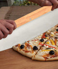 Person cutting pizza with large cutter from 5 Piece Round Pizza Stone Set With 13 Inch Stone, Oak Wood Pizza Peel, 12 By 17 Paddle, Serving Rack
