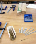 24 Piece Toggle Bolts and Wing Nuts Set for Drywall Mounting on a wood table with clamps and drill bits