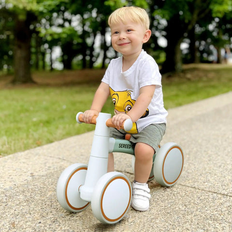 Toddler Balance Bike for 1 Year Old Baby Boys Girls First Birthday Gift No Pedal Closed Wheels with a child riding outdoors.