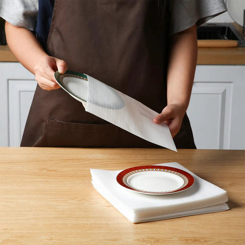 Person using Top Tier Dish Packing Kit For A No Sweat Move With 60 Heavy Duty Foam Sheets And 180 Cushioned Plate Pouches to wrap a plate.