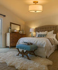 13 Inch Mid Century Modern Flush Mount Ceiling Light With Cream White Fabric Shade And Antique Brass Finish 3 Light Drum Fixture For Bedroom Dining Room Foyer And Kitchen, shown in a cozy bedroom setup