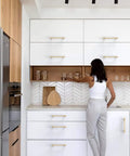 Woman using Pro Grade Brushed Gold Cabinet Pulls And Drawer Handles 5 Inch Center To Center Kitchen Hardware in modern kitchen.