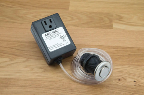 Touch Activated Garbage Disposal Air Switch Kit With Base Unit Lets You Turn On And Off With The Tap Of A Button on wooden surface