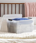 Hella Sturdy Stackable Storage Bins With Durable Plastic Build, clear bin with blue pillow on bed background.
