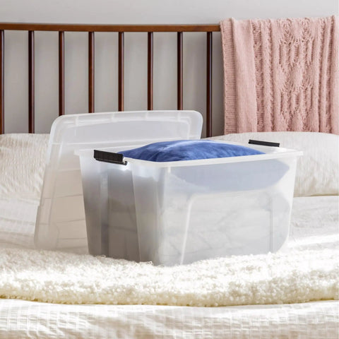 Hella Sturdy Stackable Storage Bins With Durable Plastic Build, clear bin with blue pillow on bed background.