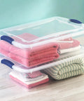 Heavy Duty 32 Quart Medium Clear Plastic Latching Storage Bin With Snap Tight Locking Lid holding folded towels in a home setting.