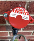 Red 2 Pack Gate Valve Lockout for 1 to 2.5 Inch Handles, installed on an outdoor faucet, preventing accidental turn on during maintenance.