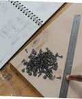 Genuine M4x10mm Carbon Steel Mini Screws With Slick Black Finish For Tight Furniture Build And Hassle Free Diy Home Improvement Projects Rock Solid Bulk Hardware Pack Today on a workbench with a ruler.