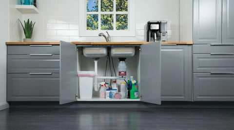 Kitchen cabinet under sink storage with open doors showing cleaning supplies and garbage bin, no disposal visible.