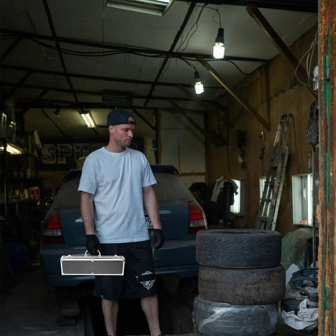 Solid Aluminum Tool Box Featuring A Slick Padded Interior And Extra Sturdy Reinforced Handle held by a man in a garage.