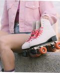 Person holding quad roller skates with pink laces showing Adjustable Elastic Brake Block For Quad Roller Skates And Ice Skates