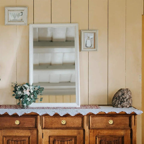 Vintage decor featuring a large mirror, floral arrangement, and brown wooden dresser with 5 pack solid unlacquered brass cabinet knobs.