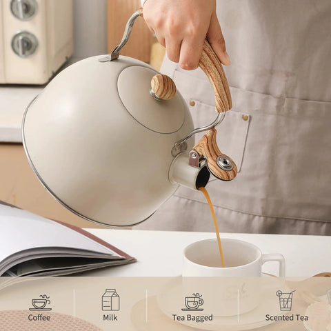 Person pouring tea from a Stove Top 2.5 Quart Whistling Tea Kettle With Food Grade 18 8 Stainless Steel Wood Pattern Folding Handle Creamy White Finish Fast Heating Easy Clean Includes Silicone Heat Insulation Pad into a mug