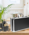 Kickass Aluminum Toolbox Carrying Case With Grip Handle Top Shelf Rigid Shell Organizer Hella Tough Storage Solution For Camera Gear Medicines Tools And Office Stationery Essentials on a wooden table next to cosmetic bottles.