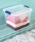 Twenty Seven Quart Clear Plastic Storage Container With Durable Blue Latches And Secure Recessed Lid Stackable Tote Bin For Hassle Free Home Organization Real Deal on a closet shelf with folded clothes.