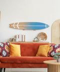 4 Piece Ash Wood Surfboard Wall Mount Kit With Curved Wave Grip mounted above an orange couch in a stylish living room.