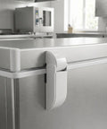 White spring loaded refrigerator door hinge on freezer, demonstrating durable iron construction and smooth swing lid.