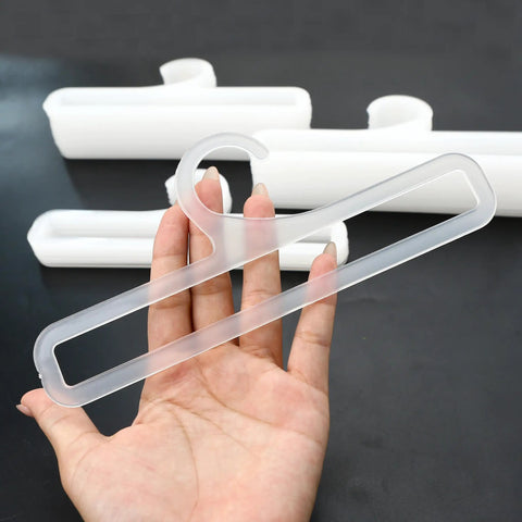 Hand holding one of the Set Of 50 White Plastic Hangers For Retail Display And Home Closet Organization, showing size and design.