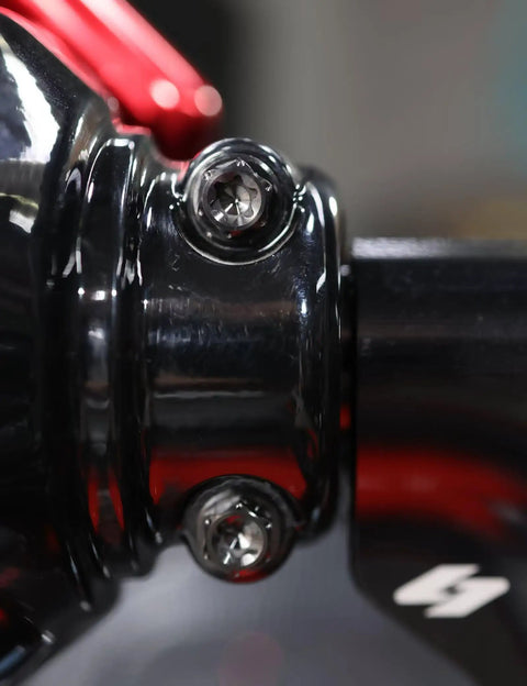 Close-up of Top Shelf Titanium Handlebar Clamp Bolts And Brake Clutch Perch Screws For Heavy Duty Motorcycles on black handlebar.