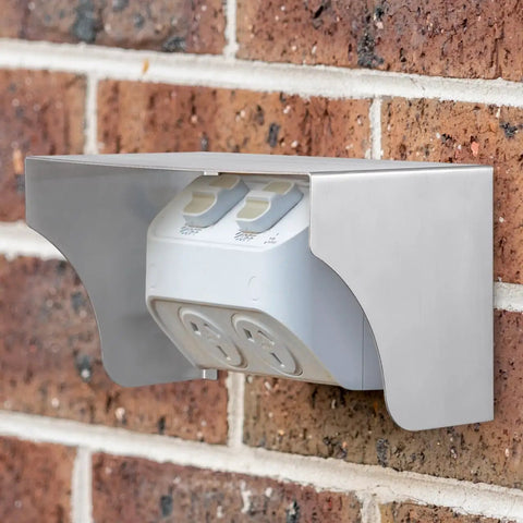 Heavy Duty Stainless Steel Weather Sealed Electrical Box Cover Rainproof Outlet Shell protecting outdoor socket mounted on a brick wall.