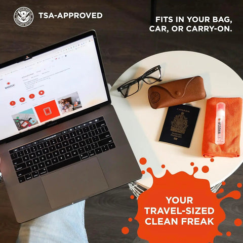 Refillable Screen Cleaner Kit With Microfiber Cloth For MacBook, iPhone, iPad And Eyeglasses next to laptop and travel items