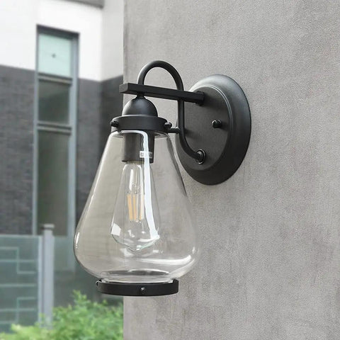 Sharp Badass Hella Waterproof Outdoor Wall Lantern With Slick Clear Glass Shade And Tough Diecast Aluminum Build For Front Porch Or Backyard Vibes Fits E27 Right Now Tonight mounted on gray wall.