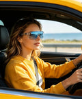 Woman wearing Straight Up Photochromic Safety Sunglasses With Polarized Optics driving in a yellow car by the sea.
