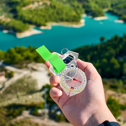 Directional Thumb Compass, MultiUse Pocket Navigation Tool for Hiking and Backpacking held over a scenic landscape