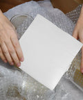 Hands placing 100 Pack White EPE Foam Bubble Pouches for bombproof shipping near fragile items like ceramics and valuables