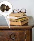 Top Tier Mini Drawer Knobs And Small Round Drawer Pulls Featuring Durable Old School Antique Finish on dresser with stacked books.