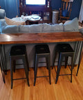 34 Inch Hairpin Table Legs Set For DIYers 1/2 Inch Dia 3 Rods Heavy Duty Metal Furniture Feet for Coffee Table TV Stand Mid Century Black with Floor Protectors 4 Pack in use on a wooden counter table behind stools.