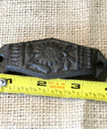 Close-up of a vintage cast iron cup pull measuring 4 inches, detailed with a floral design for drawer hardware.