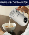 Person pouring milk from 8 In 1 Nut Milk Maker Blender 32oz Capacity For Creamy Soy Almond Oat Coconut And Plant Based Non Dairy Beverages With Delay Start And Keep Warm For Easy Homemade Milks into a bowl of cereal