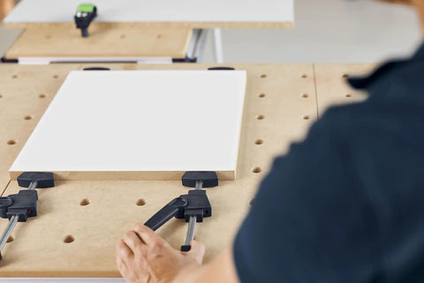 Person using Clamping Elements 2 Pack for Precise Workpiece Fixing in Woodworking on a workbench with a wooden board.