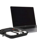 Hard Shell Tech Travel Case With All In One Cable Organizer And Mesh Pockets for adapters next to a MacBook Pro.