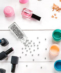 Top Shelf Rock Solid 316 Stainless Steel Paint Mixing Balls And Nail Polish Stirring Beads Smooth Rolling 4mm Metal Bearing Spheres on a work surface with nail polish bottles.