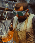 Built Heavy Duty For Real World Shop Use Ergonomic Welding Goggles With Interchangeable Lenses worn by a worker blocking sparks during welding.