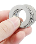 Close-up of two NTA1220 thrust needle roller bearings with washers, 1.25 in OD, steel.