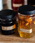 Two jars with labels: one with blueberry spread, one with maple almond spread, showing labeled jars on a wooden surface.