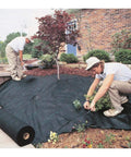 Workers installing Commercial-Grade Weed Control Fabric 4 Ft By 250 Ft in a garden, showcasing durable ground cover use.