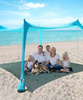 Family under 10 X 10 Ft Beach Canopy Sun Shelter with UPF50 Plus UV Protection, at a beach, includes sandbags and poles.