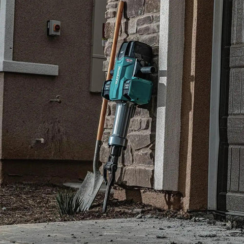 Badass Heavy Duty Eighty Volt Brushless Cordless Breaker Hammer with shovel leaning against a stone wall.