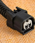 Solid VCM Bypass Harness And Resistor Plug Set For 3.5L V6 Engine connector close-up view, features dual pins and black plastic housing.