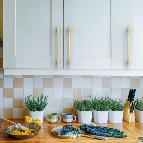 Close-up of 10 Piece 10 Inch Brushed Gold Kitchen Cabinet Handles on white cabinetry with herbs in pots.