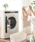 Beige Linen Cotton Seven Grid Folding Clothes Organizer Box beside woman holding shirt near washing machine in bright laundry room.