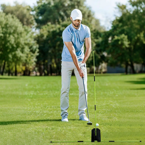 Golfer using Golf Alignment Stick Trainer With Adjustable Swing Plane Guide on outdoor grass field for swing practice.