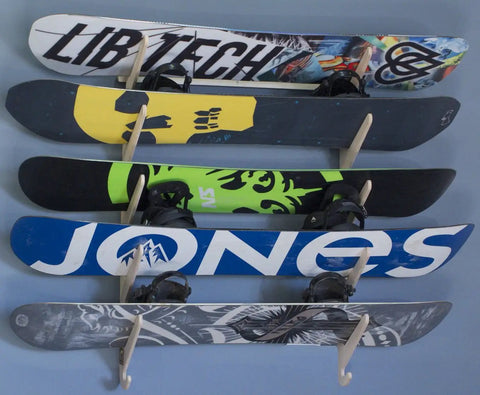 Premium Wall Rack Mount For Ski Snowboard And Longboard Storage Featuring Adjustable Baltic Birch Arms Heavy Duty Gear Holder Holds Up To One Hundred Twenty Pounds with multiple snowboards mounted.
