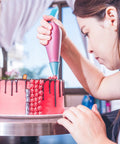 Next Level Cake Decorating Kit Featuring Hella Durable Anti Burst Piping Bags used to pipe icing on a pink cake.