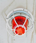Built Damn Tough Fire Sprinkler Head Protector Wire Cage Guard for ceiling mount with red light and white wire cage.